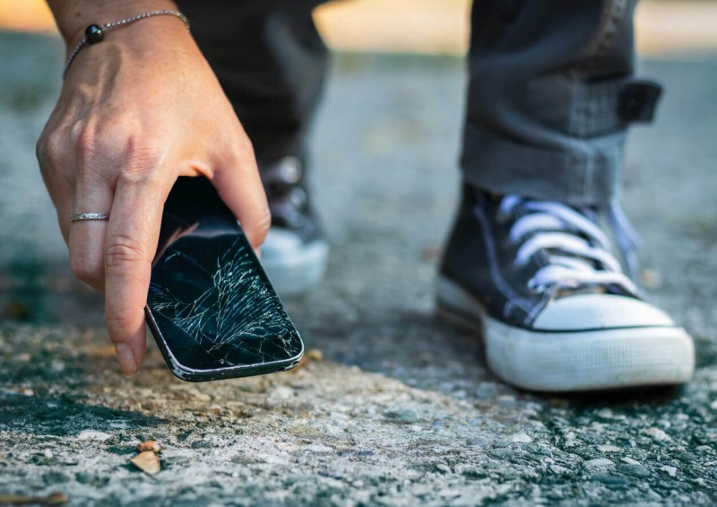 Smashed mobile phone being picked up off the floor