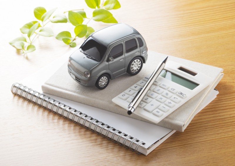 Toy car on pad of paper next to calculator