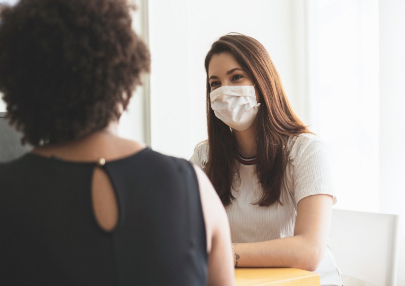 Two women talking in an office wearing facemasks