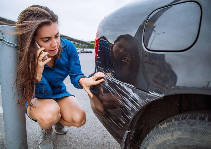 Woman checking car damage on the phone to insurance