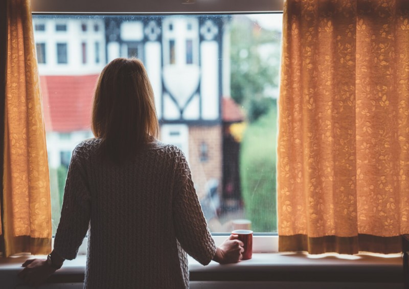 Woman looking out window during Coronavirus quarantine