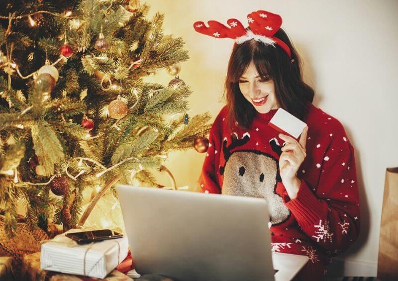 Woman shopping online with Christmas jumper and decorations