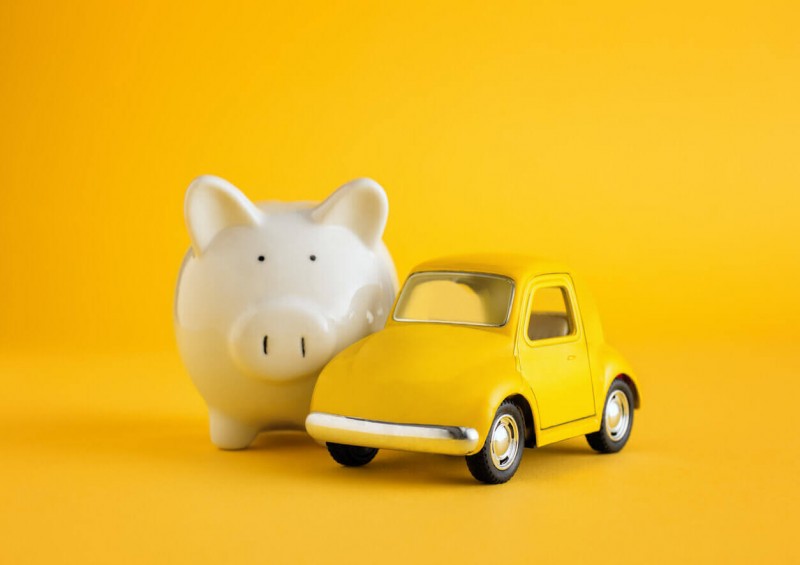 Yellow toy car next to piggy bank