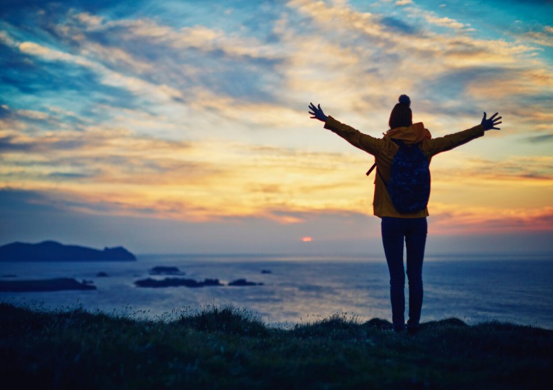Young adult with open arms to horizon