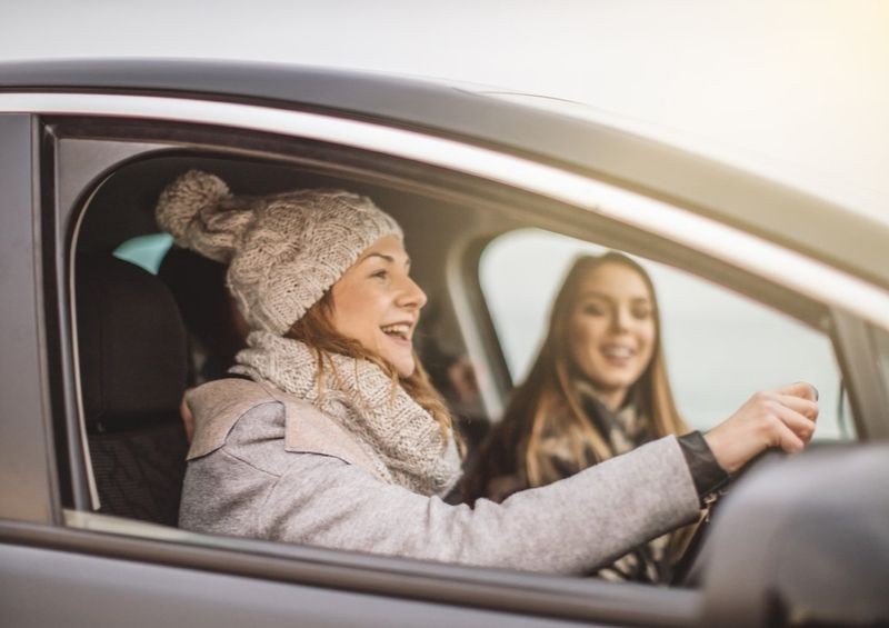 Young woman driving car with friend in passenger seat