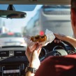 A driver eating a burger while driving