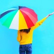 A lady standing under a brightly coloured umbrella