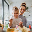 A mother painting indoors with her daughter