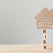 Cardboard cut out of house on top of the word risk