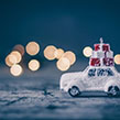 Mini car covered in snow carrying Christmas gifts