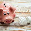 Piggy bank next to light bulb