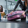 Woman with Covid mask on picking up luggage